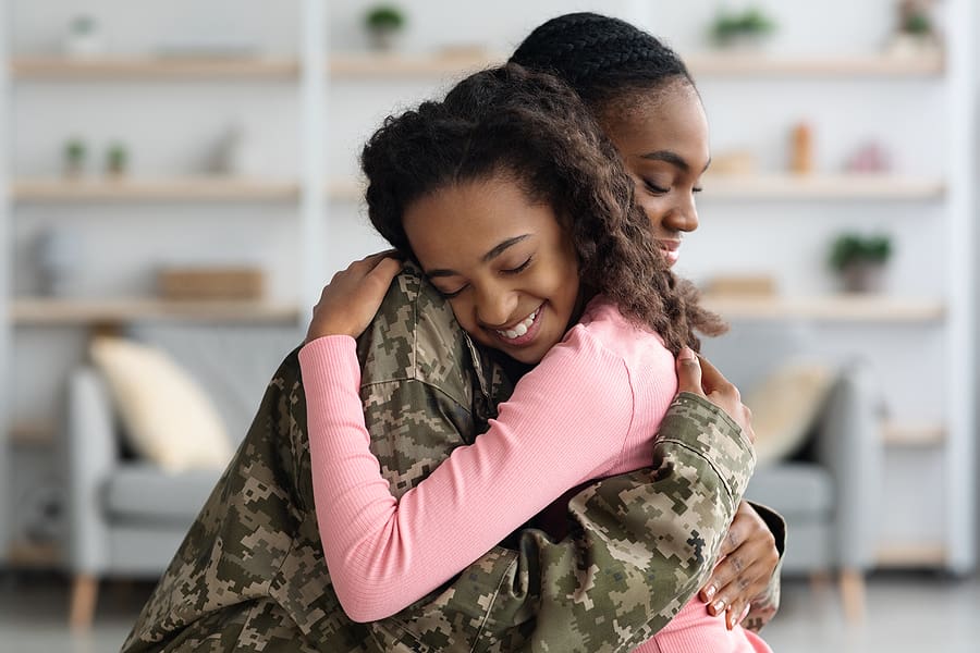 Mom in military uniform hugging young daughter