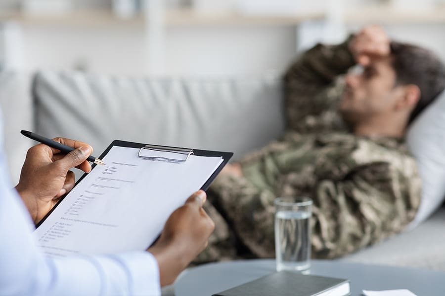 Doctor takes notes while veteran lays on couch talking