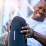 Young veteran clutches his knee in pain from a service related injury, one of the most common disabilities claimed for va benefits