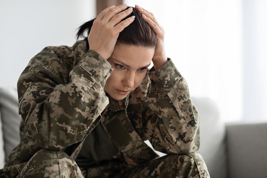 Young veteran with PTSD holding her head in her hands because she is upset