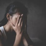 Young female veteran covering her face while dealing with the effects of sexual assault