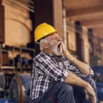 Older veteran wearing a construction hat yawning at work because he is tired due to sleep apnea