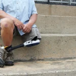 Older male veteran with a prosthetic leg and a 100% VA disability rating sitting down on steps