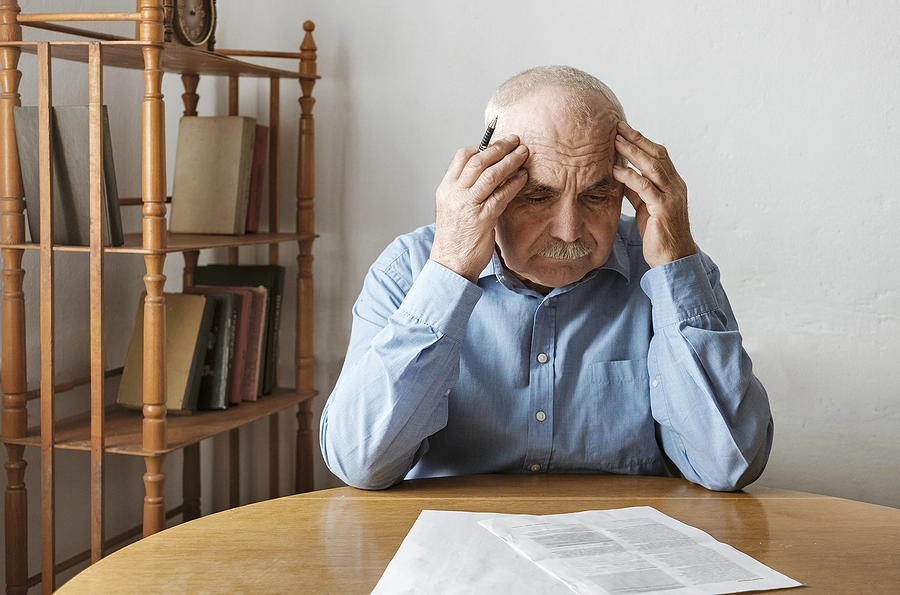 Older male veteran at his kitchen table looking at paperwork for a claim to increase his VA disability rating