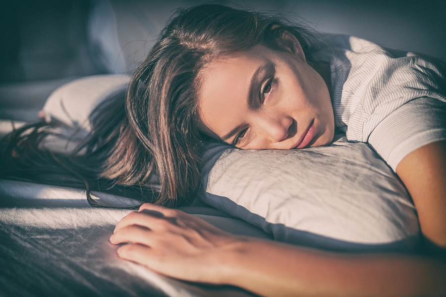 Young female veteran laying in bed during the day looking exhausted due to chronic fatigue syndrome