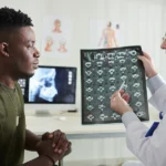Young male veteran with a sciatica VA rating talking to a doctor who is showing him a scan of his spine