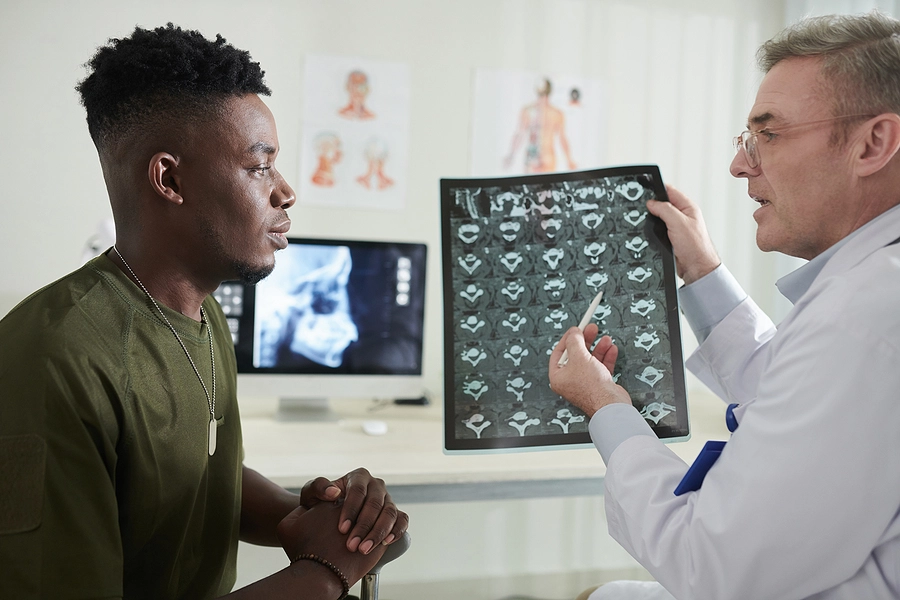 Young male veteran with a sciatica VA rating talking to a doctor who is showing him a scan of his spine