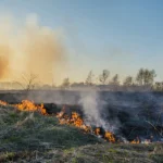 Desert landscape with the remnants of a burn pit emitting toxic smoke