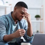 Young male veteran with service-related glaucoma struggles to see his laptop screen as he applies to receive VA disability