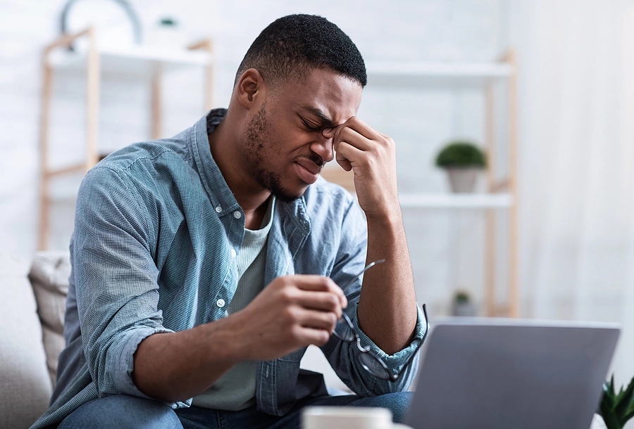 Young male veteran with service-related glaucoma struggles to see his laptop screen as he applies to receive VA disability