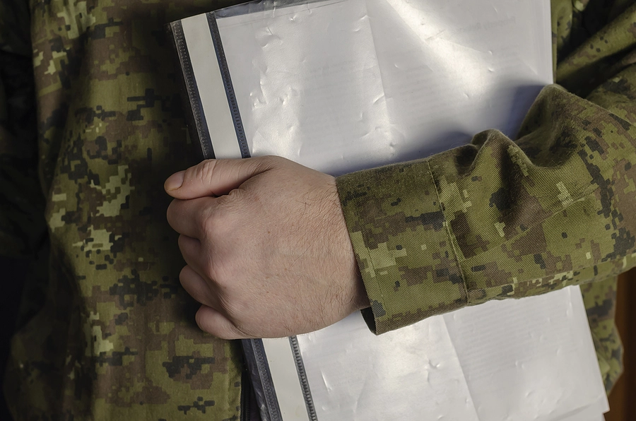 veteran in uniform holding his military service records in a folder