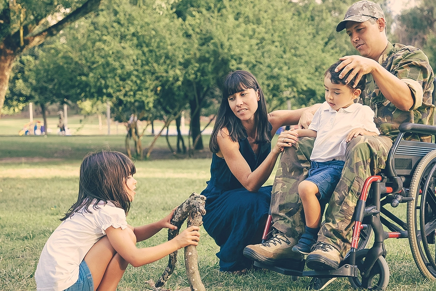 veteran with a 100% va disability rating and dependent spouse and children playing with his family in park