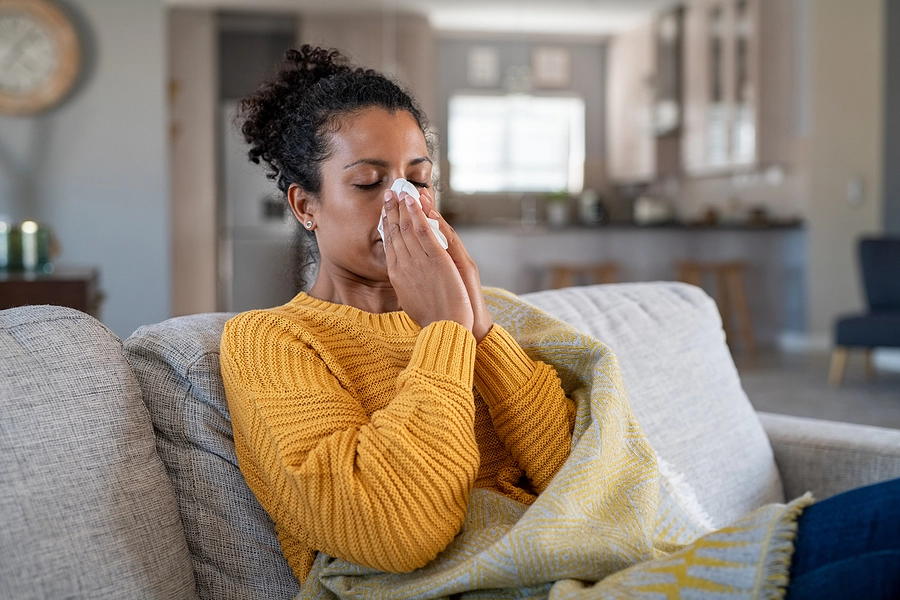 veteran with a va rating for allergic rhinitis blowing her nose in a tissue