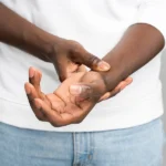 young black male veteran with a va rating for carpal tunnel holds his wrist in pain