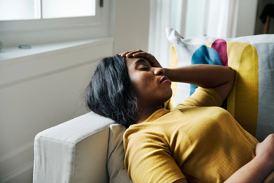 young black female veteran with chronic fatigue syndrome laying on her couch during the day looking tired